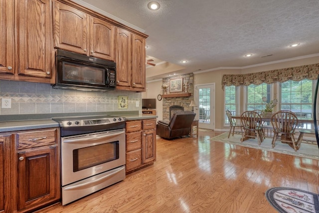 kitchen with ornamental molding, black microwave, a textured ceiling, stainless steel electric range, and light wood-style flooring