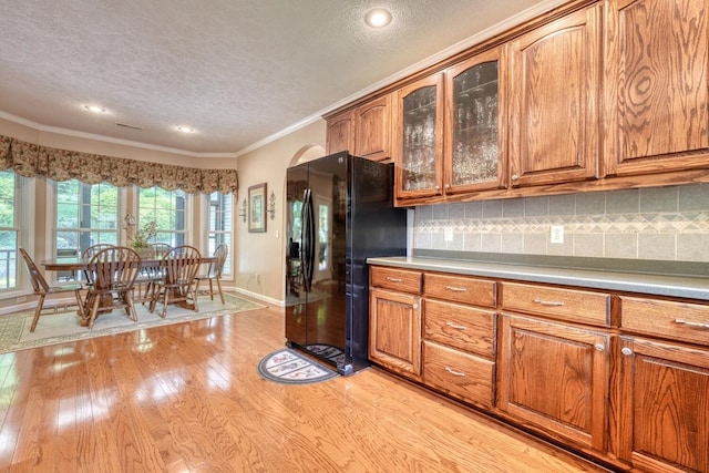 kitchen featuring light wood-style flooring, brown cabinets, and black fridge