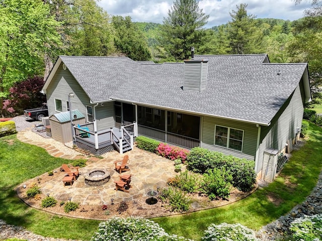 rear view of property featuring a patio, an outdoor fire pit, roof with shingles, and a chimney