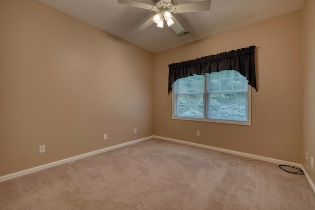 carpeted spare room featuring baseboards, ceiling fan, a textured ceiling, and visible vents