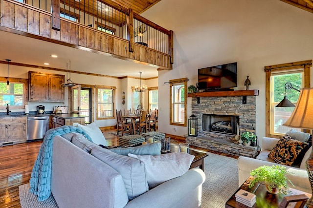 living area featuring dark wood-style floors, ornamental molding, a wealth of natural light, and a stone fireplace