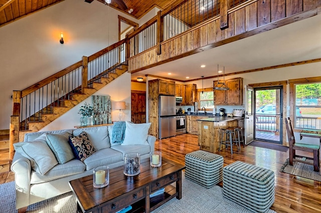 living room featuring ornamental molding, a towering ceiling, light wood finished floors, and stairs