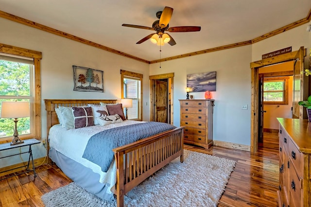 bedroom with ornamental molding, multiple windows, wood finished floors, and baseboards