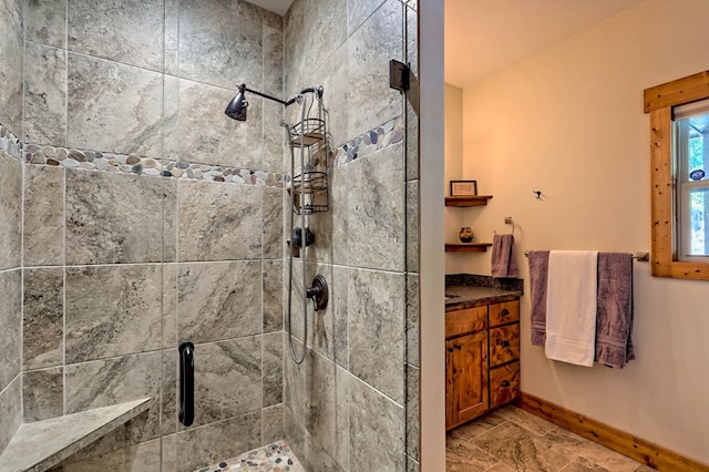 bathroom with a shower stall, baseboards, and vanity