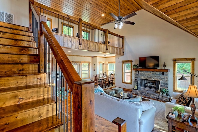 living room with plenty of natural light, wood ceiling, stairs, and a stone fireplace