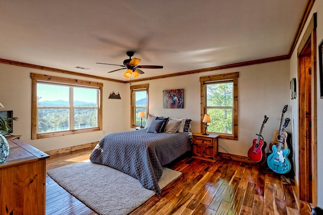 bedroom with hardwood / wood-style flooring, visible vents, baseboards, and crown molding