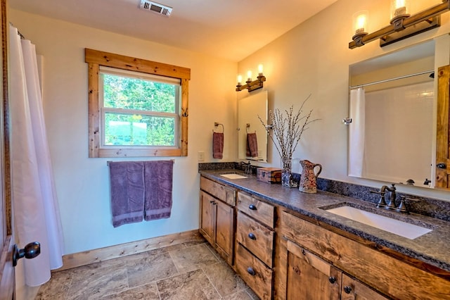 bathroom featuring stone finish floor, a sink, visible vents, and baseboards