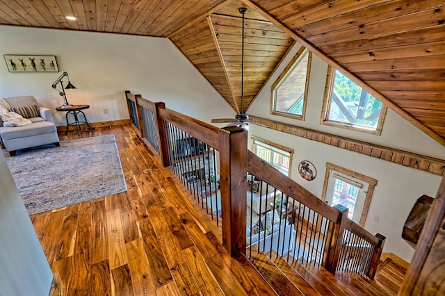 hallway featuring vaulted ceiling with skylight, baseboards, wooden ceiling, wood-type flooring, and an upstairs landing