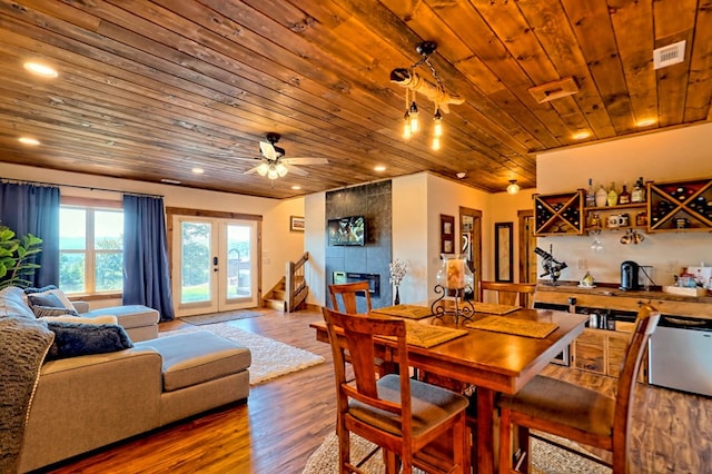 dining space with visible vents, wooden ceiling, wood finished floors, french doors, and a fireplace