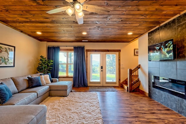 living room featuring wood finished floors, wood ceiling, french doors, stairway, and a tiled fireplace