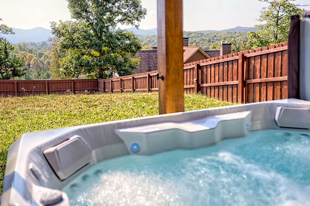 view of swimming pool featuring a fenced backyard, a mountain view, and a hot tub