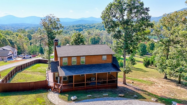 view of front of home with a shingled roof, a mountain view, a chimney, and a front lawn