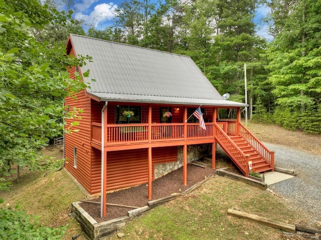 exterior space featuring metal roof, log veneer siding, driveway, and stairway