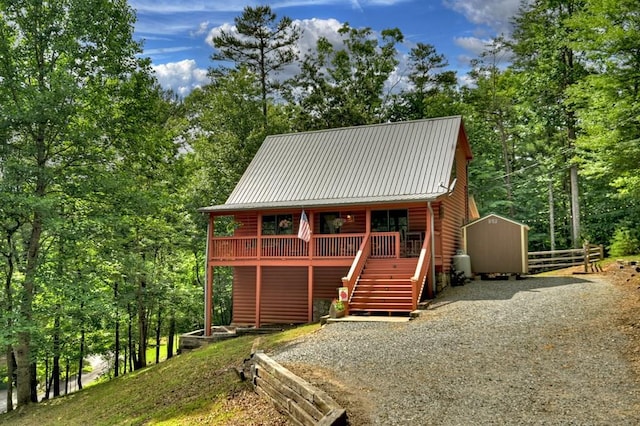 view of front of house with driveway, fence, an outdoor structure, and log veneer siding