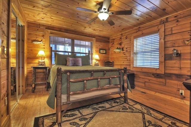 bedroom with wood ceiling, ceiling fan, light hardwood / wood-style floors, and wood walls