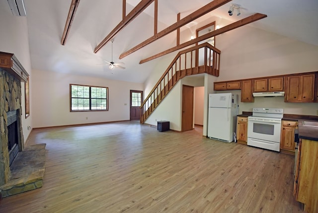 kitchen featuring a stone fireplace, white appliances, hardwood / wood-style flooring, and high vaulted ceiling