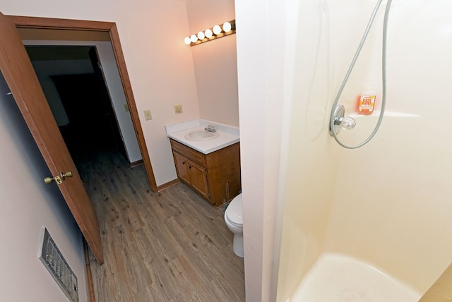 bathroom with a shower, hardwood / wood-style flooring, toilet, and vanity