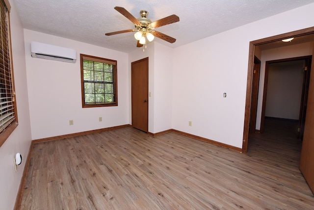 unfurnished room with wood-type flooring, ceiling fan, a textured ceiling, and a wall mounted air conditioner