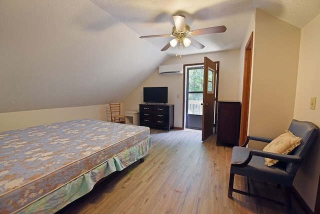 bedroom with a wall mounted air conditioner, ceiling fan, hardwood / wood-style floors, a textured ceiling, and lofted ceiling