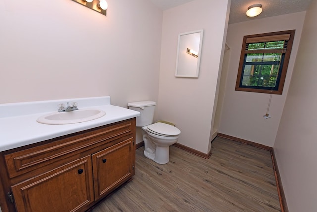 bathroom featuring wood-type flooring, vanity, toilet, and a textured ceiling