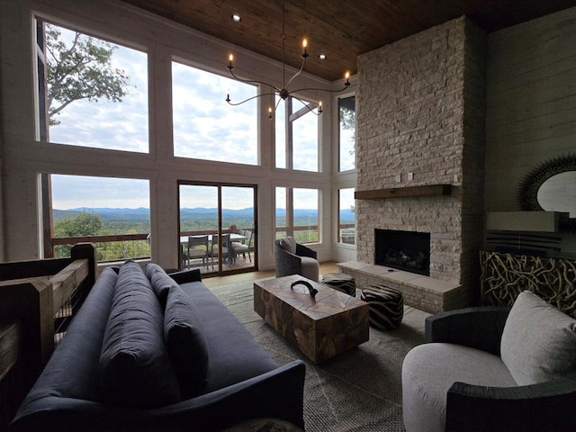 living room featuring a towering ceiling, a fireplace, wooden ceiling, a mountain view, and a notable chandelier