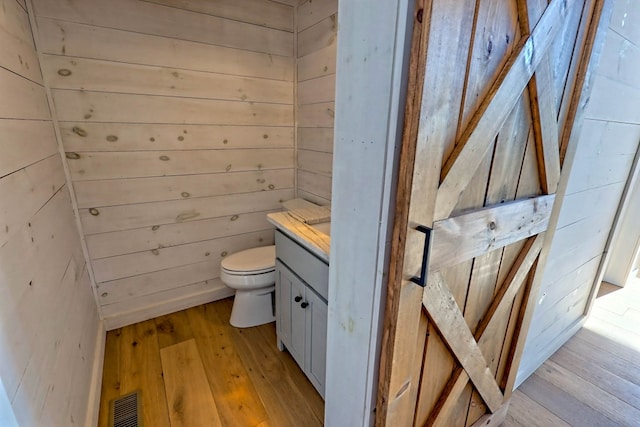 bathroom featuring vanity, visible vents, hardwood / wood-style floors, and toilet