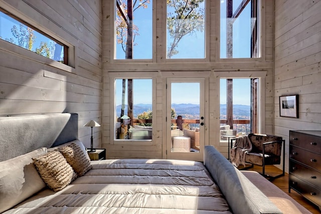 bedroom with wooden walls, a towering ceiling, access to outside, and a mountain view