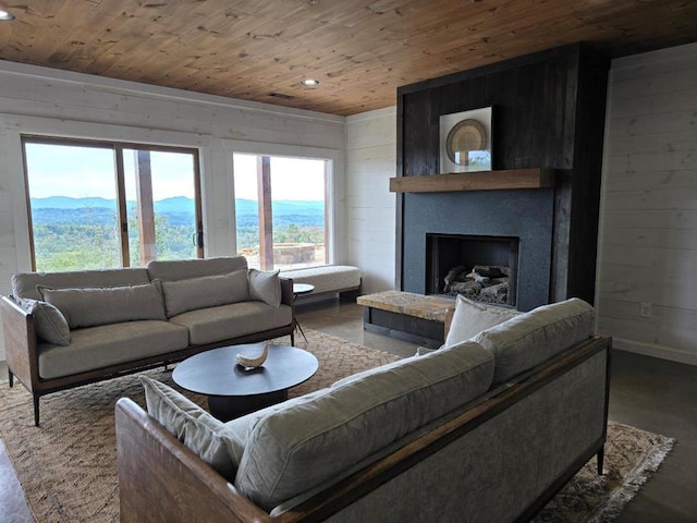 living room featuring concrete floors, wooden ceiling, a mountain view, and a fireplace