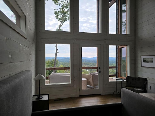 entryway with hardwood / wood-style floors, wooden walls, a mountain view, and a towering ceiling