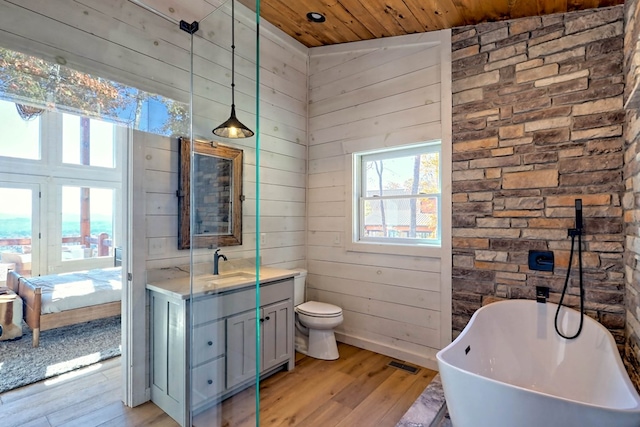 bathroom featuring vanity, a soaking tub, visible vents, wooden ceiling, and wood finished floors