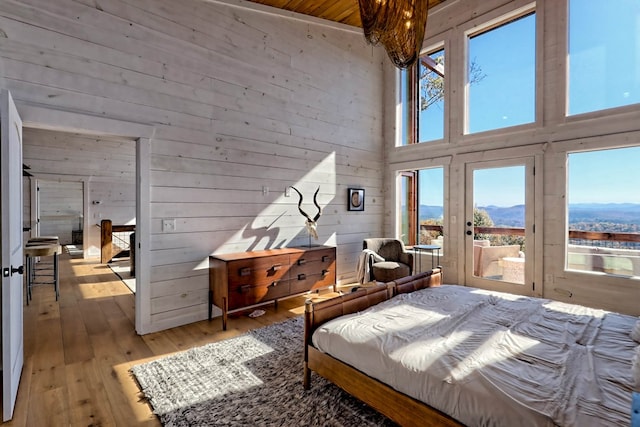 bedroom with a mountain view, a high ceiling, wood walls, access to exterior, and hardwood / wood-style floors