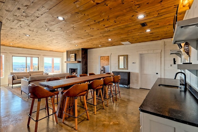 dining space with concrete flooring, wood ceiling, recessed lighting, and a fireplace
