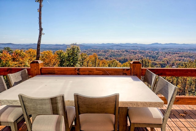 view of patio with a forest view, a deck with mountain view, and outdoor dining area