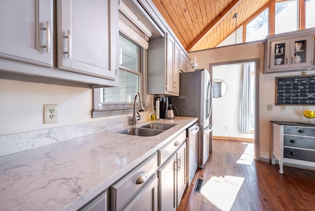 kitchen featuring stainless steel dishwasher, glass insert cabinets, vaulted ceiling, a sink, and wooden ceiling