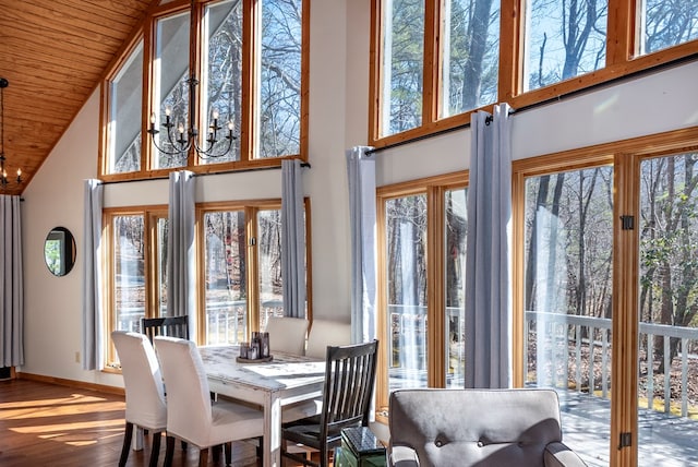 interior space featuring baseboards, a chandelier, a wealth of natural light, and wood finished floors