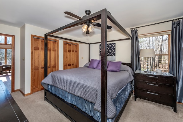 bedroom featuring a ceiling fan, a raised ceiling, light colored carpet, and baseboards