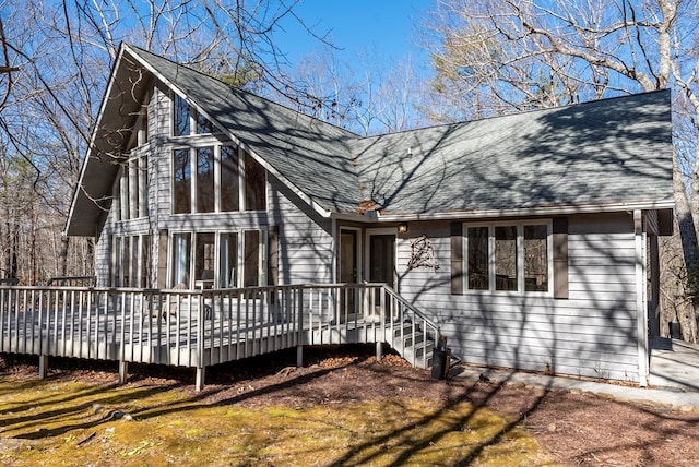 rear view of house featuring roof with shingles and a wooden deck