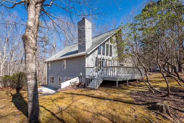 rear view of property with a chimney, a yard, and a deck