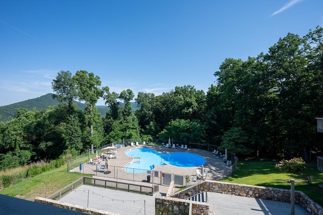 pool featuring fence, a mountain view, a patio, and a yard