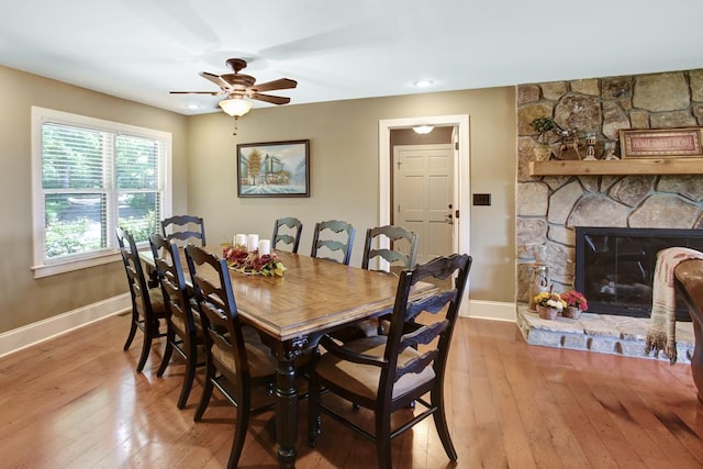 dining room featuring ceiling fan, a fireplace, and light hardwood / wood-style floors