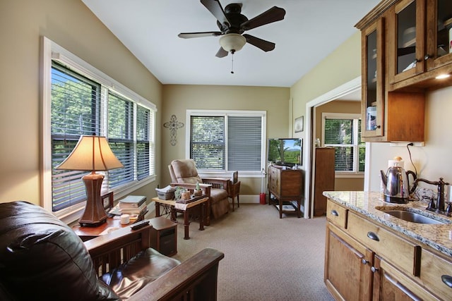 living area featuring ceiling fan, sink, light colored carpet, and plenty of natural light