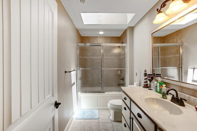 full bathroom featuring a skylight, tile patterned flooring, enclosed tub / shower combo, toilet, and vanity