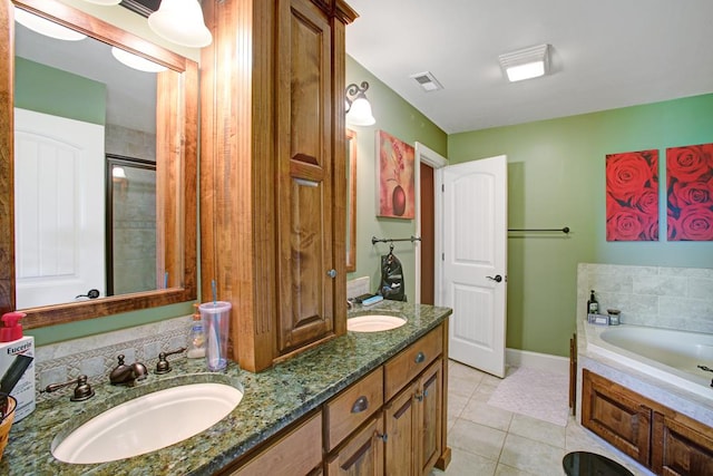 bathroom with a washtub, vanity, and tile patterned floors