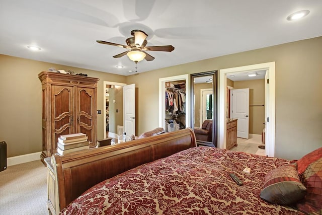 bedroom with ensuite bathroom, ceiling fan, a spacious closet, light colored carpet, and a closet