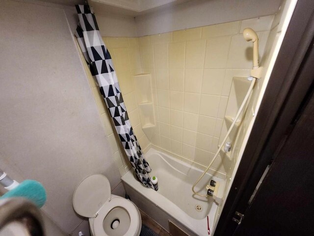 bathroom with toilet and shower / bath combo with shower curtain