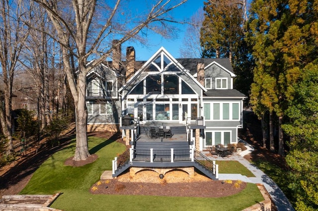 back of property featuring a wooden deck and a lawn