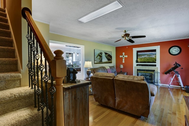 living room featuring wood-type flooring, a textured ceiling, a fireplace, and ornamental molding