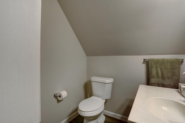 bathroom with vaulted ceiling, vanity, and toilet