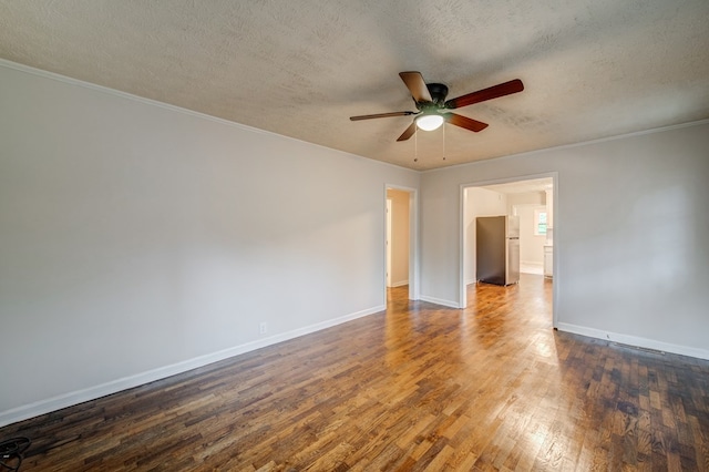 empty room with crown molding, a textured ceiling, baseboards, and dark wood-type flooring