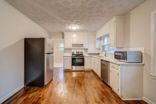 kitchen featuring dark wood-style floors, appliances with stainless steel finishes, a sink, and white cabinets